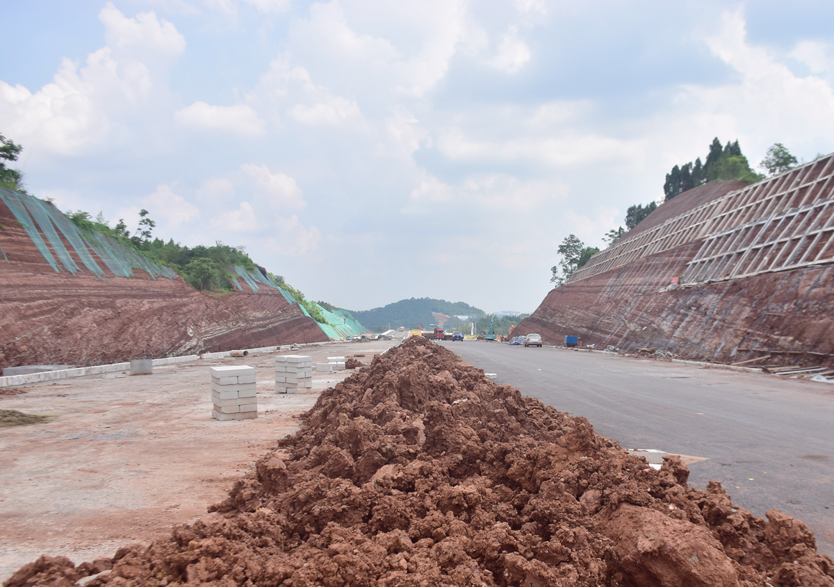 被挖断的山丘旁,工人正在进行堡坎施工,以防止山体落石.